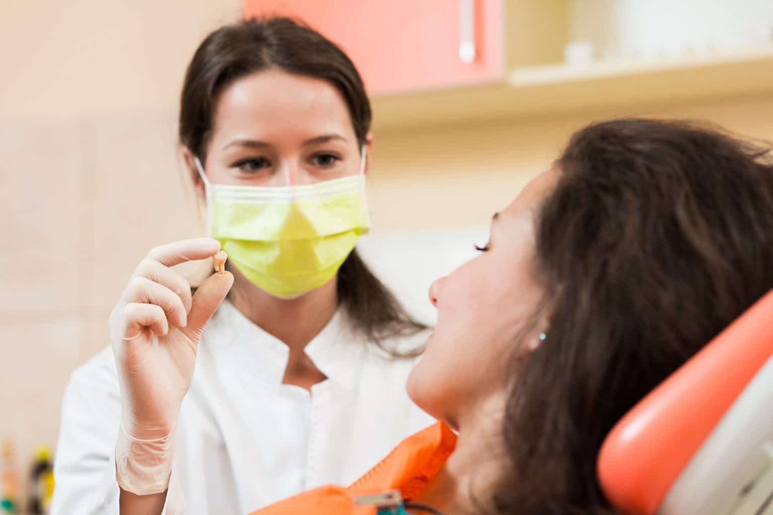 Dentist woman holding patient's tooth in hand