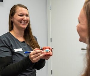 dental hygienist showing patient how to brush teeth at Singla Dental in Duncanville,TX
