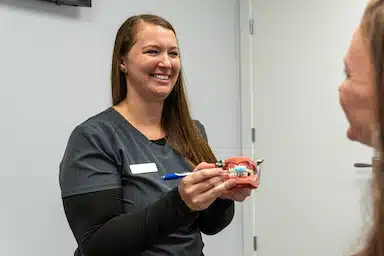 dental hygienist showing patient how to brush teeth at Singla Dental in Duncanville,TX