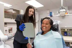 Dental Assistant showing patient her smile in the mirror at Singla Dental in Duncanville,TX