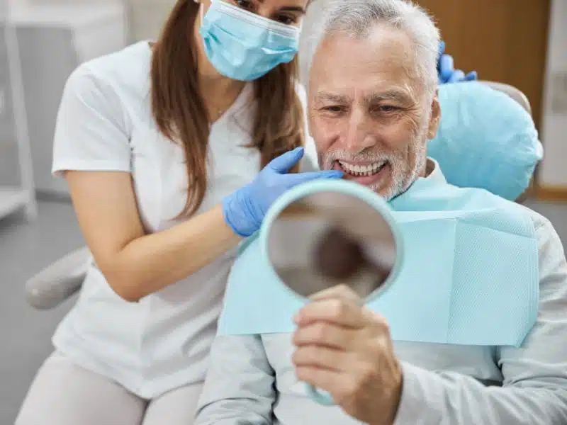 A senior patient admiring their smile after getting dental implants