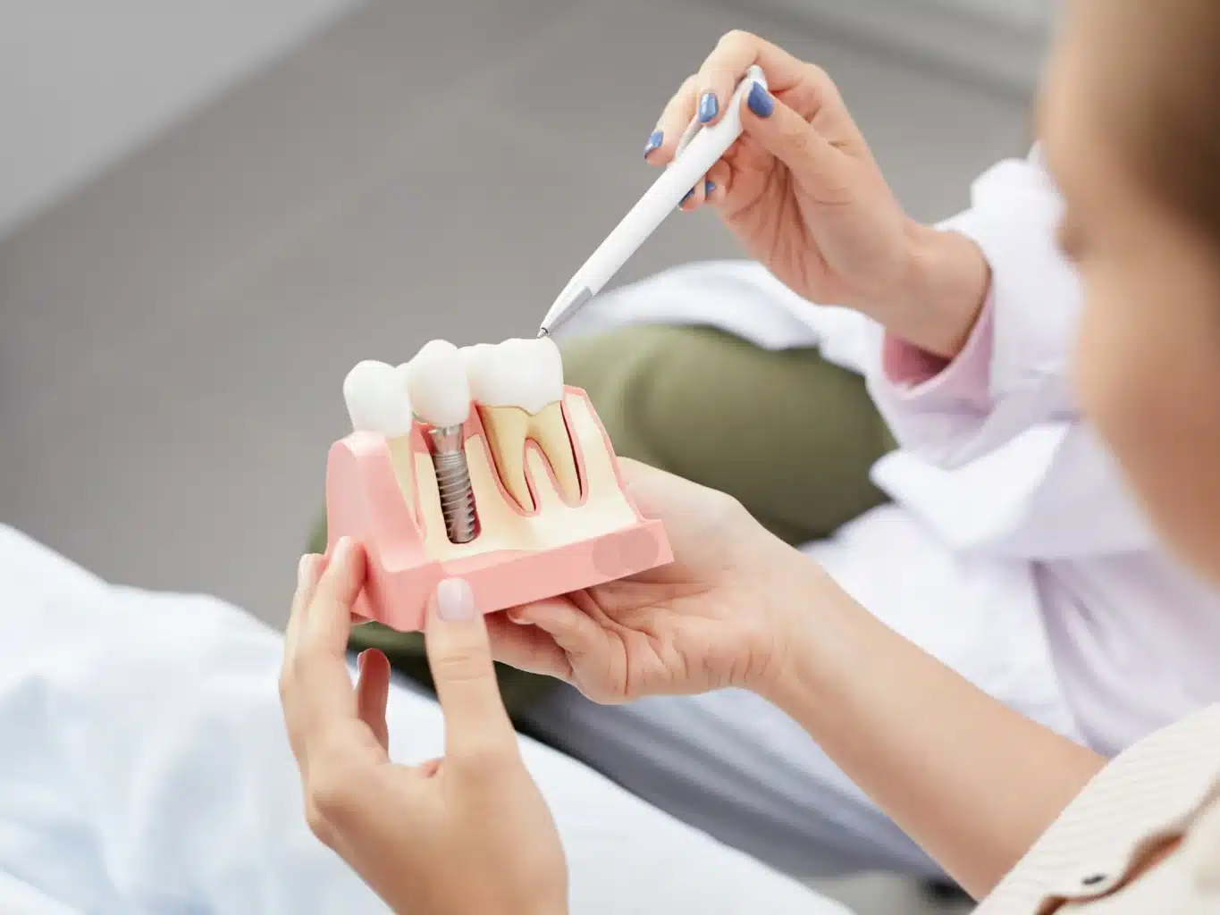 a dentist explaining dental implants to a patient using a model