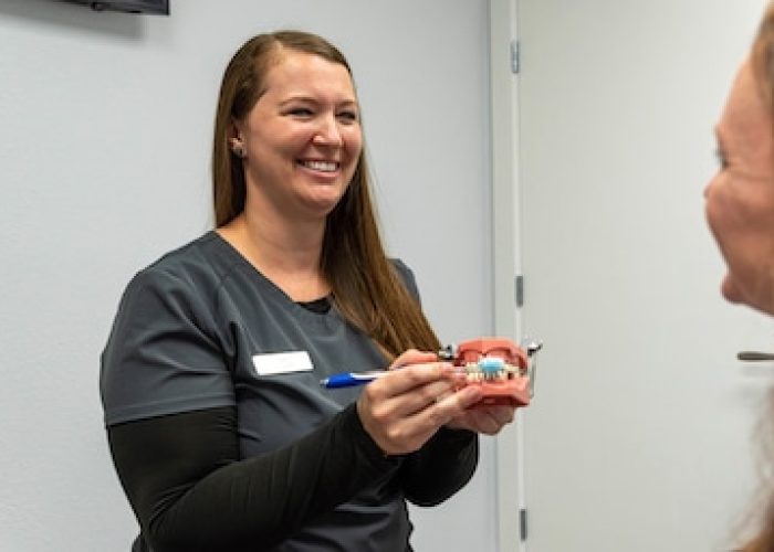 dental hygienist showing patient how to brush teeth at Singla Dental in Duncanville,TX