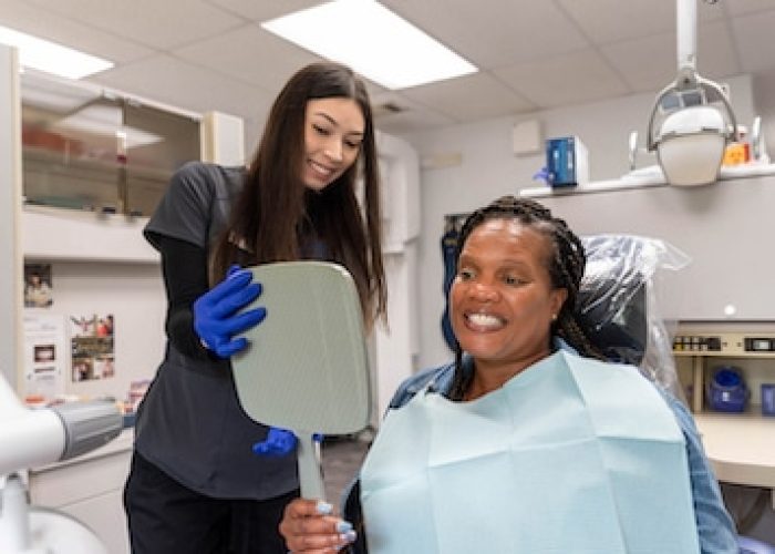 Dental Assistant showing patient her smile in the mirror at Singla Dental after visiting cosmetic dentist in Duncanville,TX